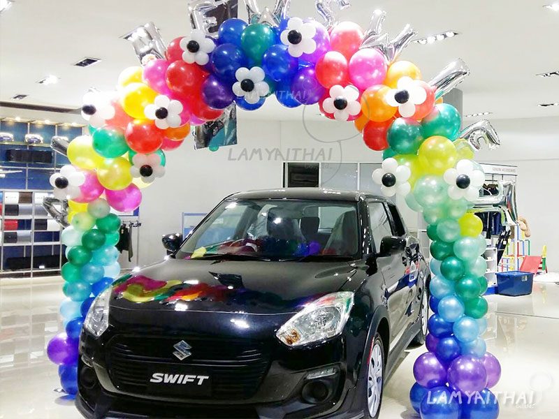 ซุ้มลูกโป่งหลากสีรูปดอกไม้ คร่อมรถ Suzuki Swift ในโชว์รูมรถยนต์