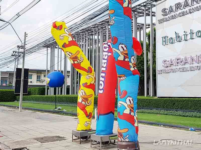 ท่อผ้าสกายทูปพิมพ์ลายการ์ตูนเป็ดสีเหลืองน้ำเงินตั้งริมถนนหน้าโครงการ