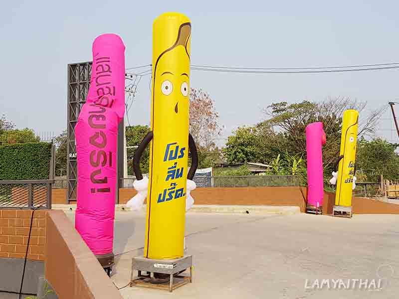 สกายทูปการ์ตูนสีเหลืองชมพูพิมพ์ข้อความโปรโมชั่นหน้าทางเข้าโครงการ
